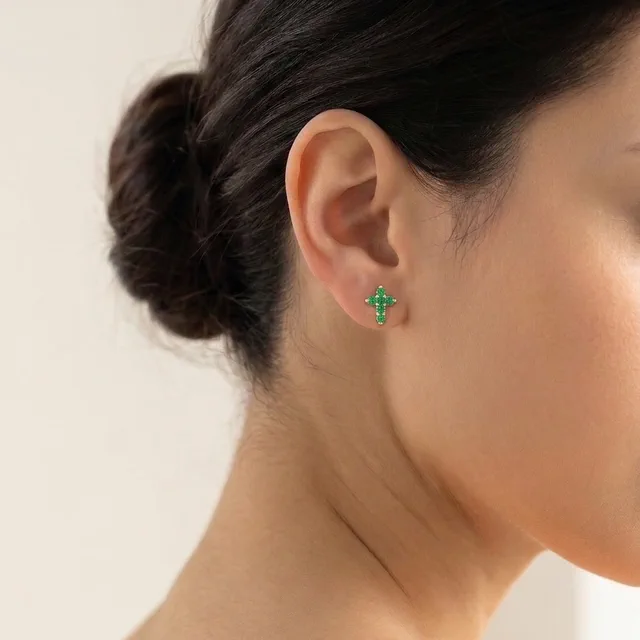 Topo cruz en oro 18K con circones verdes puesto en la oreja
